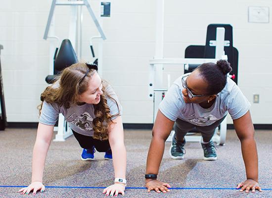 两个在线博彩的学生在健身房锻炼. 